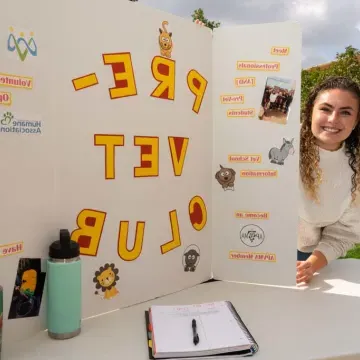 Female student at student org fest for Pre-Vet club table